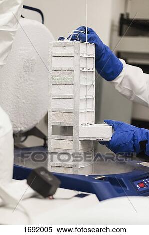 Stock Photography - Cropped image of scientist holding frozen storage compartment at laboratory. Fotosearch
