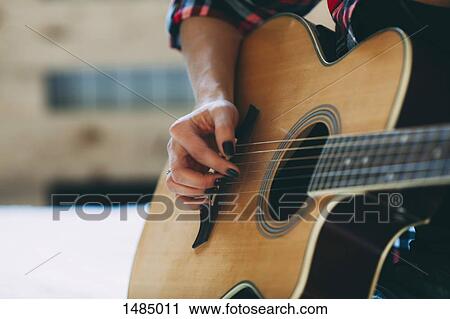 Cropped image of woman playing guitar at home View Large Photo Image Stock Image - Cropped image of woman playing guitar at home. Fotosearch