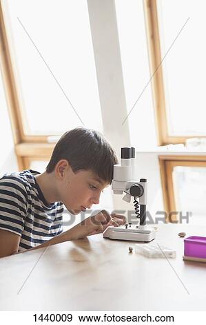 Curious boy using microscope on table at home View Large Photo Image Stock Photo - Curious boy using microscope on table at home. Fotosearch