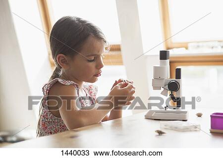 Curious girl looking at specimen with microscope on table at home View Large Photo Image Stock Image - Curious girl looking at specimen with microscope on table at home. Fotosearch
