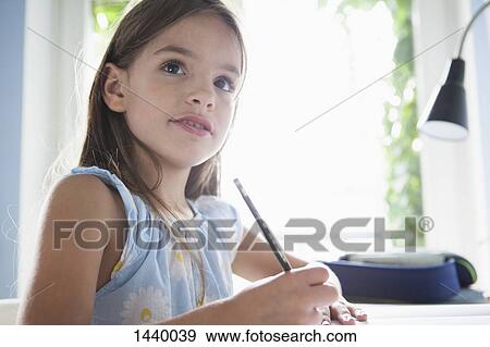 Stock Photo - Cute girl doing homework at table. Fotosearch