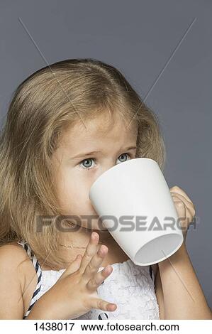 Cute girl drinking coffee against gray background View Large Photo Image Stock Photo - Cute girl drinking coffee against gray background. Fotosearch