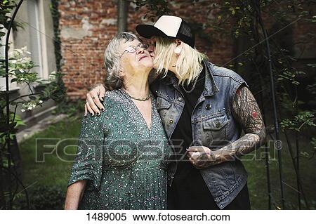 Stock Photography - Daughter kissing mother while standing in back yard. Fotosearch