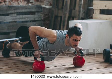 Dedicated man exercising with kettlebells at gym View Large Photo Image Stock Image - Dedicated man exercising with kettlebells at gym. Fotosearch