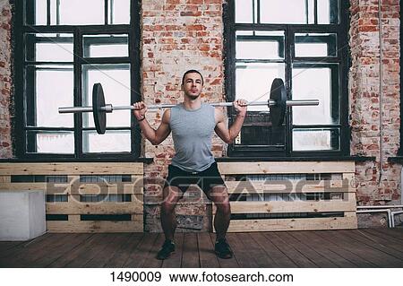 Determined man lifting barbell at gym View Large Photo Image Stock Photo - Determined man lifting barbell at gym. Fotosearch