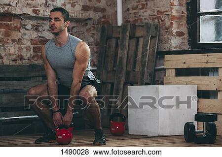 Determined man lifting kettlebell at gym View Large Photo Image Stock Photo - Determined man lifting kettlebell at gym. Fotosearch