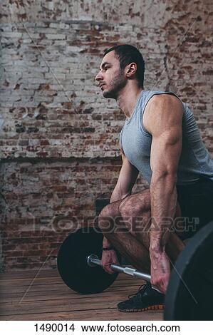 Determined young man lifting barbell at gym View Large Photo Image Picture - Determined young man lifting barbell at gym. Fotosearch