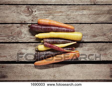 Stock Image - Directly above shot of various carrots on wooden table. Fotosearch