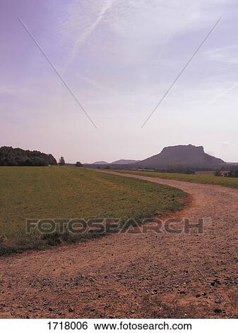 Dirt road amidst grassy field against sky, Elbsandstein Mountains, Saxony, Germany View Large Photo Image Stock Photograph - Dirt road amidst grassy field against sky, Elbsandstein Mountains, Saxony, Germany. Fotosearch