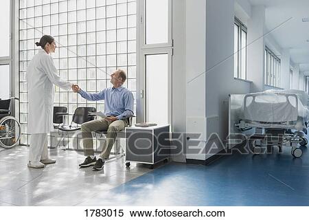 Doctor greeting, shaking hands with patient in hospital waiting room View Large Photo Image Stock Photography - Doctor greeting, shaking hands with patient in hospital waiting room. Fotosearch