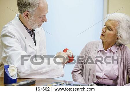 Doctor holding anatomical model while explaining to senior woman at clinic View Large Photo Image Stock Image - Doctor holding anatomical model while explaining to senior woman at clinic. Fotosearch