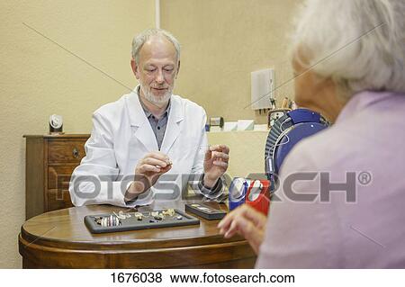Doctor with hearing aids explaining to senior woman at clinic View Large Photo Image Stock Photo - Doctor with hearing aids explaining to senior woman at clinic. Fotosearch