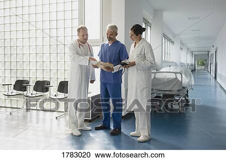 Doctors discussing medical chart in hospital corridor View Large Photo Image Stock Image - Doctors discussing medical chart in hospital corridor. Fotosearch