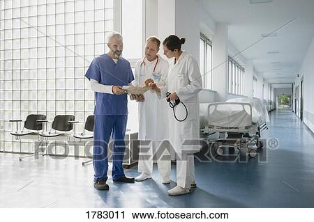 Stock Image - Doctors discussing medical record in hospital corridor. Fotosearch