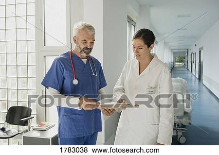 Stock Photo - Doctors discussing medical record in hospital corridor. Fotosearch
