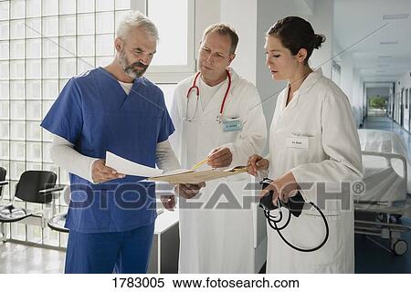 Stock Photography - Doctors discussing medical record in hospital corridor. Fotosearch