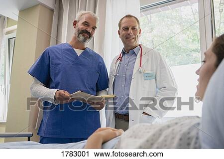 Doctors making rounds, talking with patient in hospital room View Large Photo Image Stock Image - Doctors making rounds, talking with patient in hospital room. Fotosearch