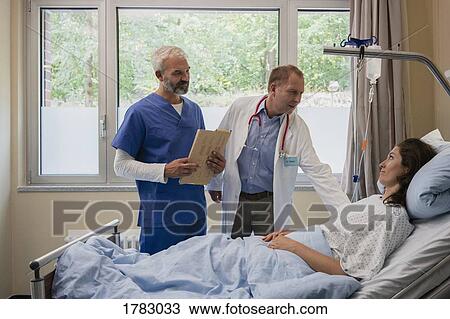 Doctors making rounds, talking with patient in hospital room View Large Photo Image Stock Image - Doctors making rounds, talking with patient in hospital room. Fotosearch