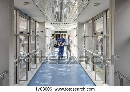 Doctors talking and walking in hospital corridor View Large Photo Image Stock Photograph - Doctors talking and walking in hospital corridor. Fotosearch