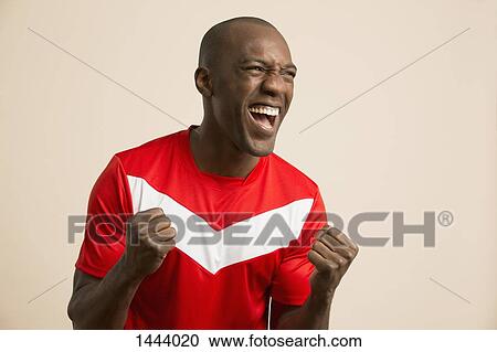 Excited soccer player cheering against colored background View Large Photo Image Stock Image - Excited soccer player cheering against colored background. Fotosearch