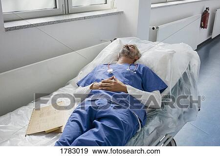 Exhausted doctor resting, sleeping on stretcher in hospital corridor View Large Photo Image Stock Photo - Exhausted doctor resting, sleeping on stretcher in hospital corridor. Fotosearch