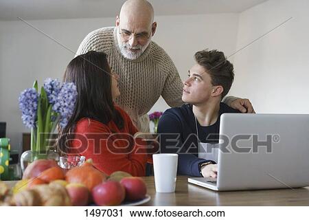 Family talking by table with laptop at home View Large Photo Image Stock Image - Family talking by table with laptop at home. Fotosearch