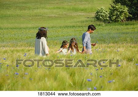 Picture - Family walking in sunny, idyllic rural green field with wildflowers. Fotosearch