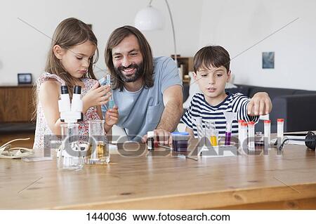 Father and children doing science experiment on table in house View Large Photo Image Stock Photograph - Father and children doing science experiment on table in house. Fotosearch