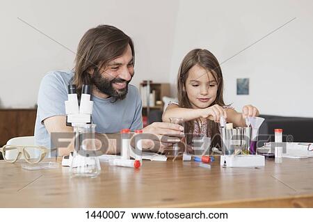 Stock Photo - Father and daughter working on science project at home. Fotosearch