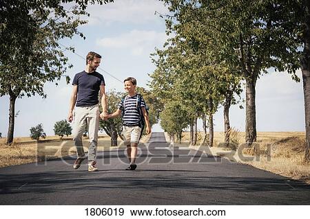 Father and schoolboy sun holding hands, walking down sunny road View Large Photo Image Stock Photo - Father and schoolboy sun holding hands, walking down sunny road. Fotosearch