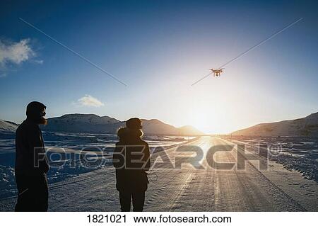 Father and son flying drone over remote, snow covered road, Reykjadalur, Iceland View Large Photo Image Stock Image - Father and son flying drone over remote, snow covered road, Reykjadalur, Iceland. Fotosearch