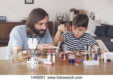 Stock Image - Father and son working on science experiment at home. Fotosearch