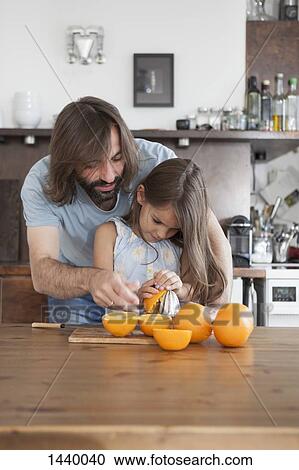 Father assisting daughter to squeeze oranges from juicer on table at home View Large Photo Image Stock Image - Father assisting daughter to squeeze oranges from juicer on table at home. Fotosearch