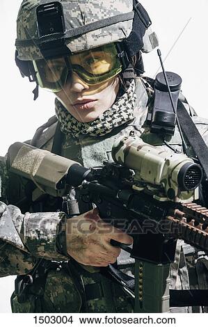 Picture - Female army soldier carrying rifle standing against white background. Fotosearch