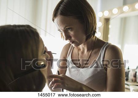 Stock Photo - Female artist applying make-up on fashion model. Fotosearch