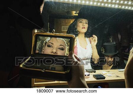 Stock Photo - Female burlesque performers getting ready at mirrors in backstage dressing room. Fotosearch
