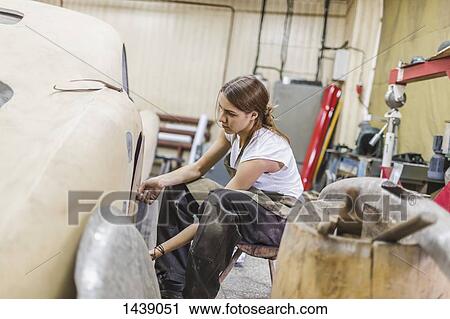 Stock Image - Female mechanic repairing car at repair shop. Fotosearch