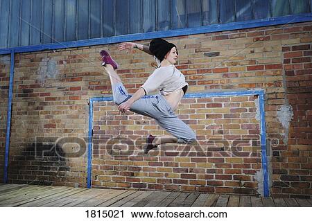 Stock Image - Female modern dancer performing against brick wall. Fotosearch