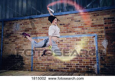 Stock Image - Female modern dancer performing with spray paint cans. Fotosearch