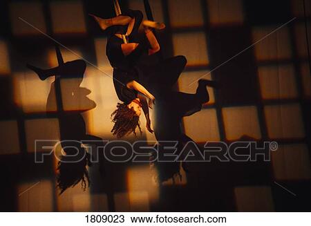 Stock Image - Female performer hanging from rope on stage. Fotosearch