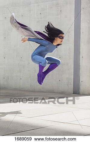 Female superhero levitating in mid-air against wall View Large Photo Image Stock Photo - Female superhero levitating in mid-air against wall. Fotosearch