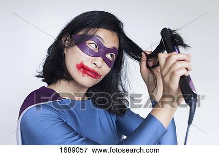 Female superhero with smudged lipstick straightening hair against gray background View Large Photo Image Stock Photo - Female superhero with smudged lipstick straightening hair against gray background. Fotosearch