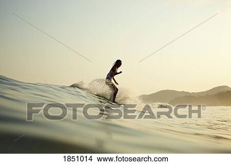 Female surfer riding ocean wave View Large Photo Image Picture - Female surfer riding ocean wave. Fotosearch