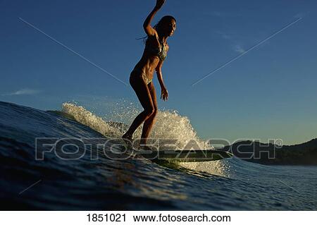 Stock Image - Female surfer riding ocean wave. Fotosearch