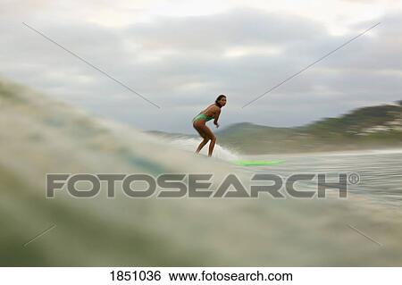 Stock Photograph - Female surfer riding ocean wave. Fotosearch