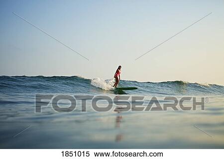 Stock Photography - Female surfer riding ocean wave. Fotosearch