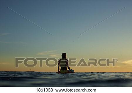 Female surfer waiting on surfboard on ocean at sunset View Large Photo Image Stock Image - Female surfer waiting on surfboard on ocean at sunset. Fotosearch