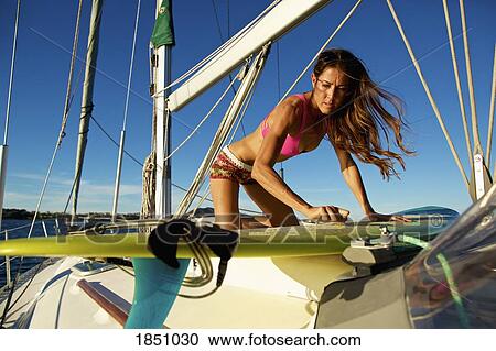 Female surfer waxing surfboard on sunny sailboat View Large Photo Image Stock Image - Female surfer waxing surfboard on sunny sailboat. Fotosearch
