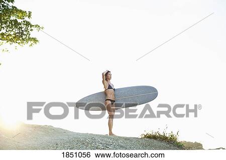 Female surfer with surfboard on rock View Large Photo Image Stock Photograph - Female surfer with surfboard on rock. Fotosearch