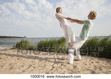 Friend balancing on man's knee at beach against sky View Large Photo Image Stock Photograph - Friend balancing on man's knee at beach against sky. Fotosearch